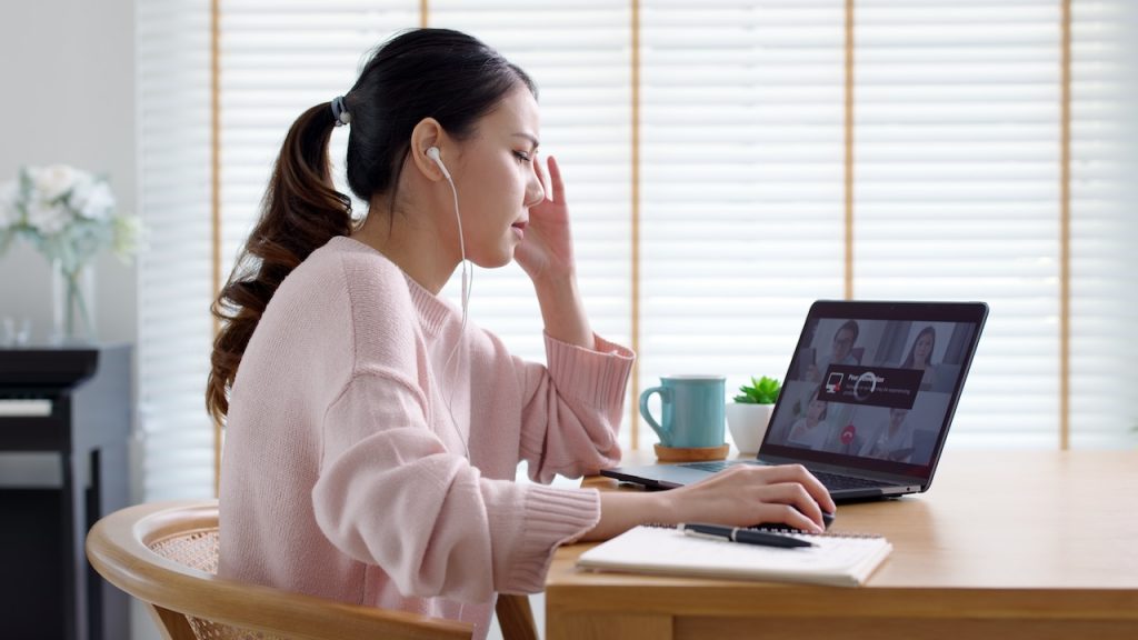 Back rear view young asian woman employee work from home using computer notebook videocall meeting conference angry annoy with low poor unreliable internet wifi connection problem issue outage.