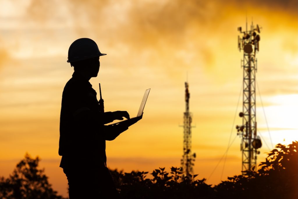 A telecommunication engineer monitors network infrastructure to optimize 5G advanced networks and pave the way for next-generation 6G connectivity. This visualizes edge computing deployment, open RAN architecture, cloud-native networks, and cybersecurity protocols essential for modern IoT and hyper-connected smart cities.
